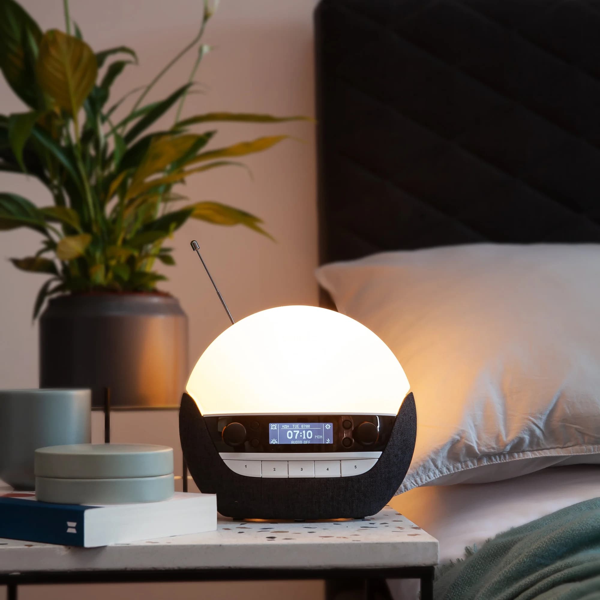 Lumie 750 DAB Luxe auf dem Nachttisch neben dem Bett, die Anzeige zeigt 07:10